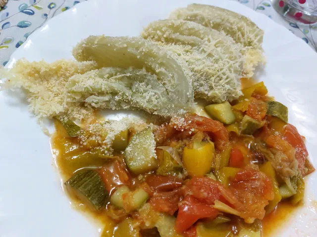 Des tranches de fenouil cuites au four couvertes de parmesan râpé et de chapelure, servies avec une poêlée de courgettes et de poivrons