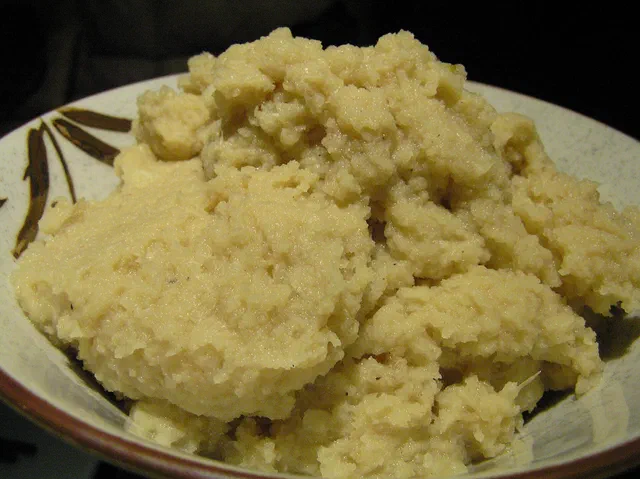 Une purée de panais et chou-fleur couleur crème, en tas irrégulier dans une assiette décorée de feuilles brunes