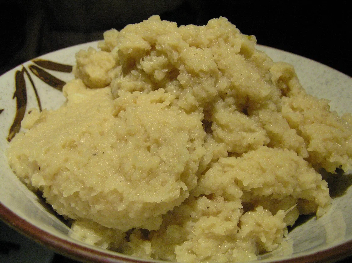 Une purée de panais et chou-fleur couleur crème, en tas irrégulier dans une assiette décorée de feuilles brunes