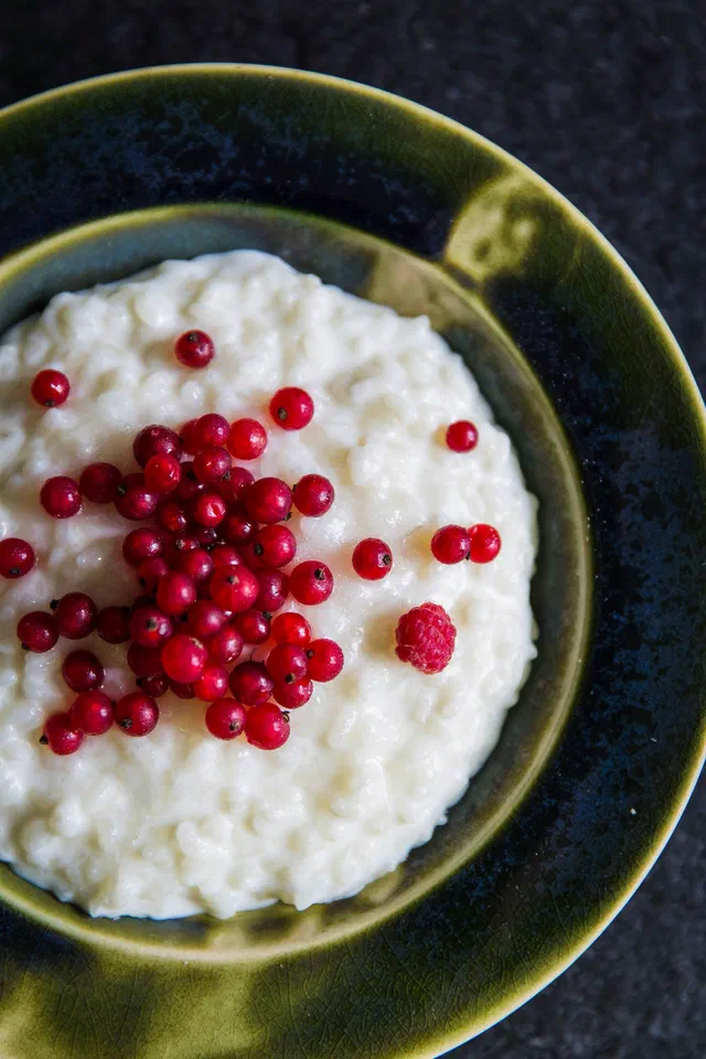 Une assiette creuse de riz au lait crémeux garni de groseilles, vue de dessus