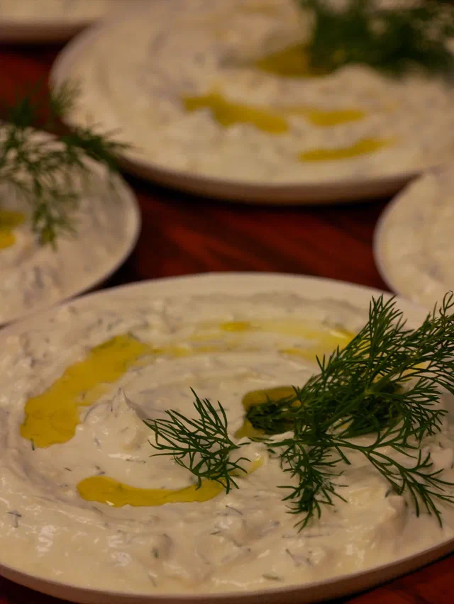 Des assiettes de tzatziki crémeux arrosé d'un filet d'huile d'olive et garni de brins d'aneth frais